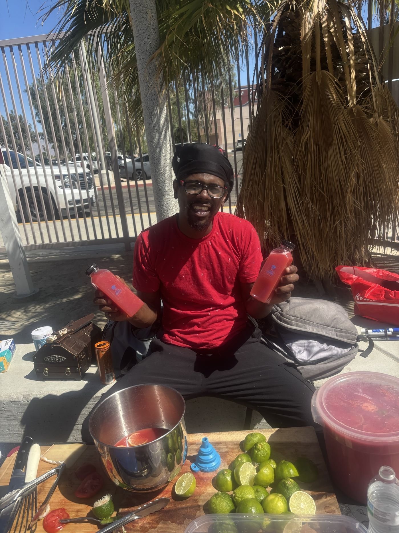 Chef Merder holding two bottles of fresh juice at a prep table with limes